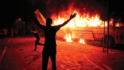 TOPSHOT - Protesters shout slogans after setting a bus on fire during a demonstration outside the ...