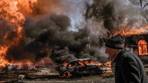 TOPSHOT - A Ukrainian woman walks past flames and smoke rising from a fire following an artillery ...