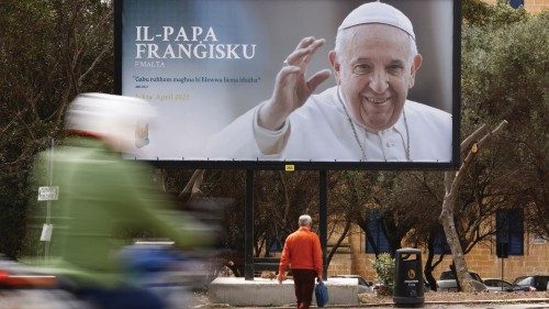 A man walks near a billboard promoting Pope Francis' upcoming visit to Malta, in Floriana, Malta ...