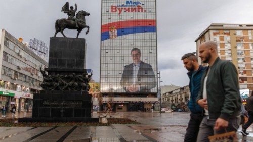 People walk by a huge election campaign billboard featuring Aleksandar Vucic on the hotel Ambasador, ...