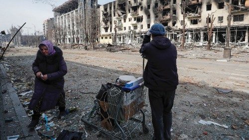 Residents stand with their belongings on a street near a building burnt in the course of ... Residents stand with their belongings on a street near a building burnt in the course of ...