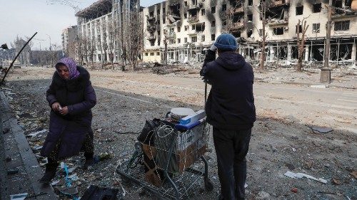 Residents stand with their belongings on a street near a building burnt in the course of ...