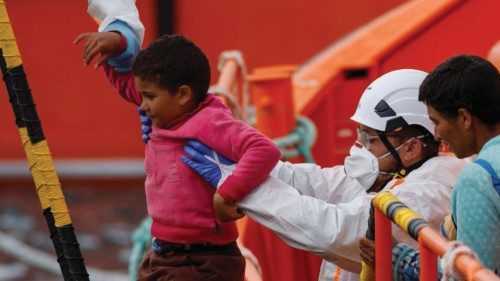 Rescuers help a migrant child to disembark from a Spanish coast guard vessel, in the port of ...