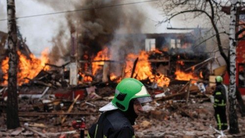 A firefighter stands next to a burning building, following a missile attack near the Kharkiv ...