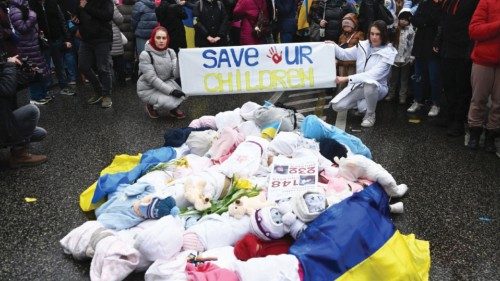 epa09866317 Demonstrators rally with the Ukrainian flag and baby dolls representing victims of ...
