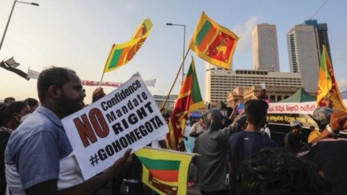epa09898775 Protesters shout slogans and wave Sri Lankan flags during the day and night protest in ...