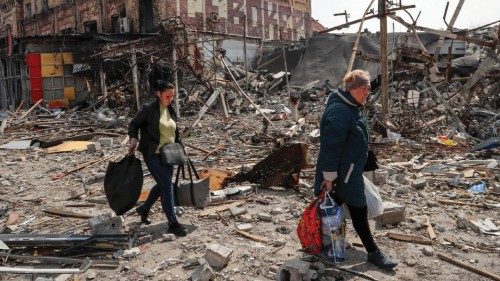 Residents carry their belongings near buildings destroyed in the course of Ukraine-Russia conflict, ...