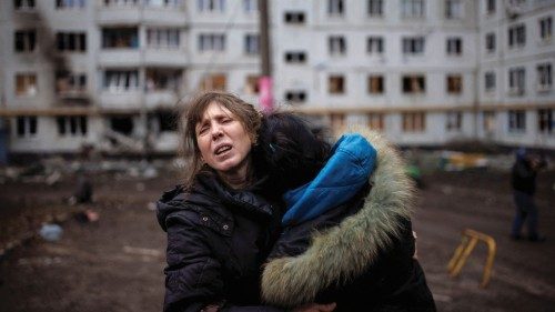 A woman reacts as she hugs another woman outside a heavily damaged apartment block, following an ...