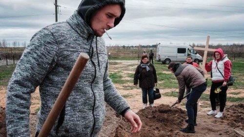 Oleksandr Smagliuk (L), 21, helps to bury the coffin of his relative Mykhailo Romaniuk, who was shot ...