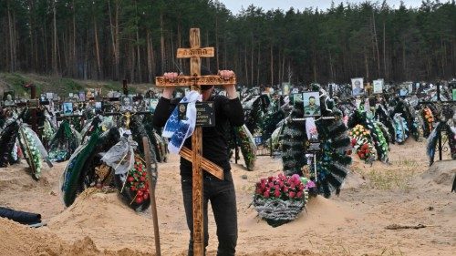 TOPSHOT - A communal worker sets a cross on a grave during a funeral at a cemetery in Irpin on April ...