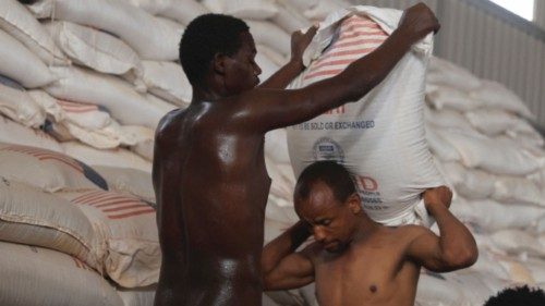 Men hold a sack of wheat at a World Food Program (WFP) warehouse, at a camp for people displaced by ...