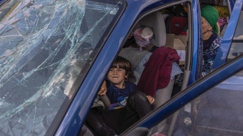 epa09923265 A boy plays in a car with a broken front window after arriving from Mariupol at the ...