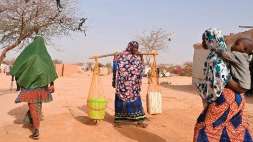 A woman carries containers at an internally displaced persons (IDP) camp in Ouallam, Niger, on May ...