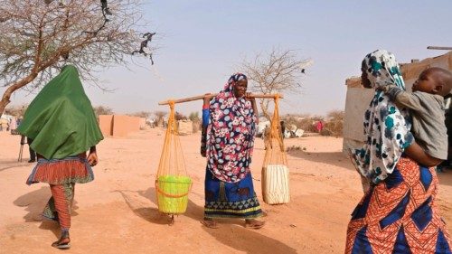A woman carries containers at an internally displaced persons (IDP) camp in Ouallam, Niger, on May ... A woman carries containers at an internally displaced persons (IDP) camp in Ouallam, Niger, on May ...