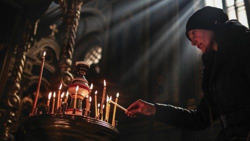epa09852772 A Ukrainian woman lights a candle while people pray inside the St. Elijahs Monastery ...