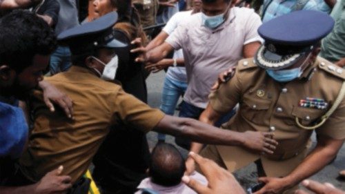 Police officers try to protect a supporter of Sri Lanka's ruling party during a clash with ...