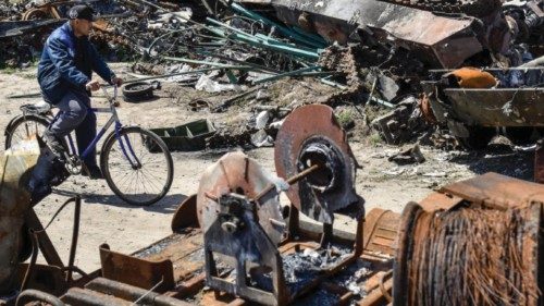 epa09937869 A man cycles past debring at a junkyard in Bucha, Ukraine, 10 May 2022. On 24 February, ...