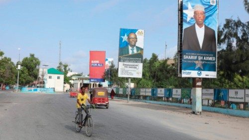 A Somali man cycles past election banners of presidential candidates along a street in Mogadishu on ...