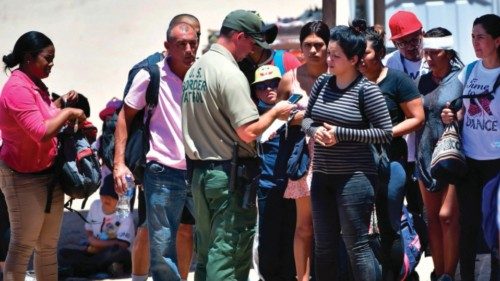 A US Customs and Border Protection (CPB) officer tends to migrants on the Mexico side of the border ...