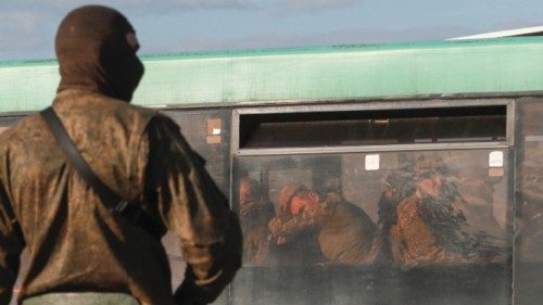 A service member of pro-Russian troops stands guard on a road near a bus carrying Ukrainian ... A service member of pro-Russian troops stands guard on a road near a bus carrying Ukrainian ...