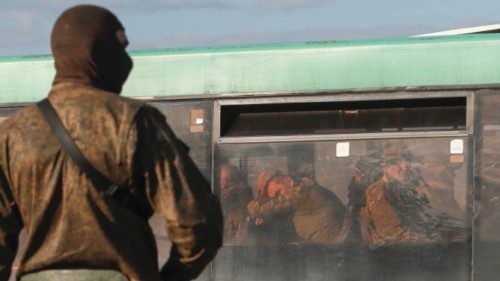 A service member of pro-Russian troops stands guard on a road near a bus carrying Ukrainian ...