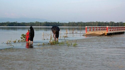 People make their way through a flooded road after heavy rains in Sylhet on May 23, 2022. - At least ...