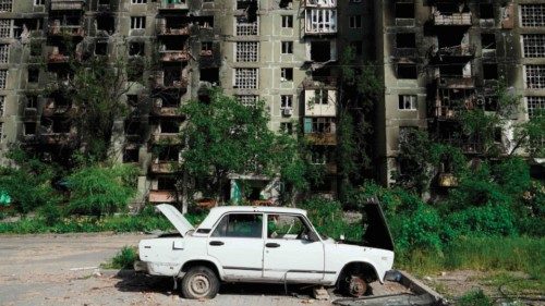 A damaged car is pictured in front of a destroyed residential building in Mariupol on May 31, 2022, ...
