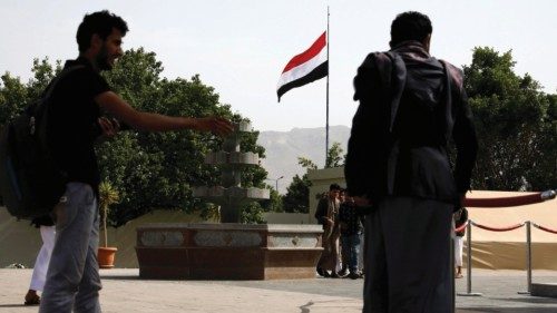 epa09991960 Yemenis stand in front of a Yemeni flag on the eve of a renewed truce in Sana'a, Yemen, ...