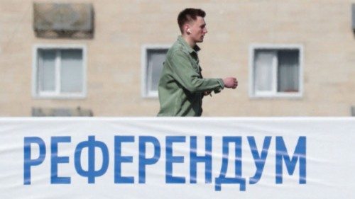 A man walks along a bridge near a banner informing of the upcoming referendum in Almaty, Kazakhstan ...