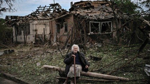 An eldery woman sits in front of destroyed houses after a missile strike, which killed an old woman, ...