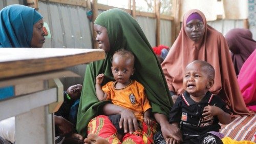 Internally displaced Somali women sit with their children as they wait for malnutrition screening at ...