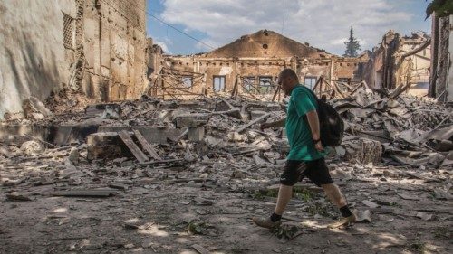 A local resident walks in a front of a building destroyed by a military strike, as Russia's attack ...