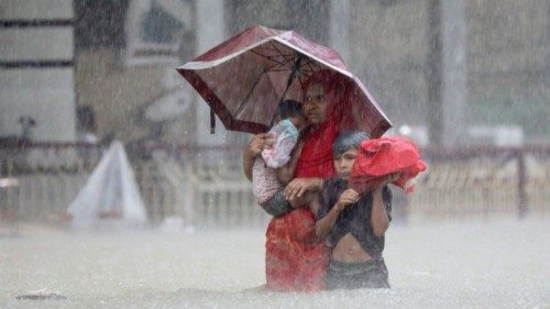 People wade through the water as they look for shelter during a flood, amidst heavy rains that ...