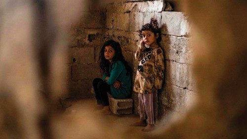 Syrian girls, displaced with their family from Deir Ezzor, looks at the camera inside the damaged ...