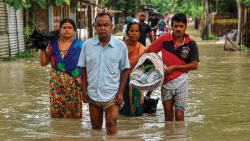 People wade through flood waters in Solmara of Nalbari district, in India's Assam state on June 19, ...