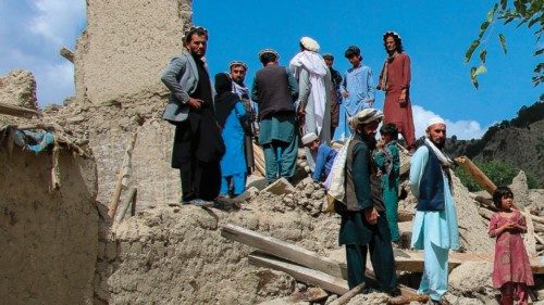 Afghan men talk amongst themselves as they look for their belongings amid the ruins of damaged ...