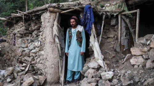 Barakatullah poses for a picture in front of his house that was damaged by an earthquake in Spolgin ...