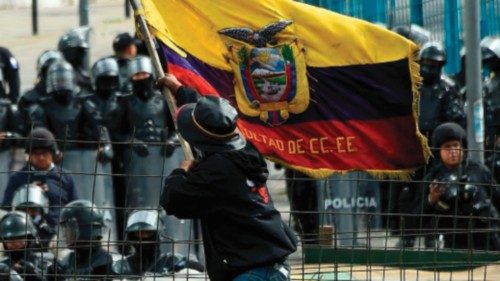 TOPSHOT - A demonstrator waves an Ecuadorean national flag while police officers stand guard in the ...