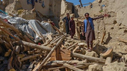 Afghan men gesture as they look for their belongings amid the ruins of damaged houses after an ...
