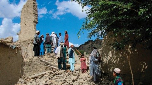 Afghan men talk amongst themselves as they look for their belongings amid the ruins of damaged ...