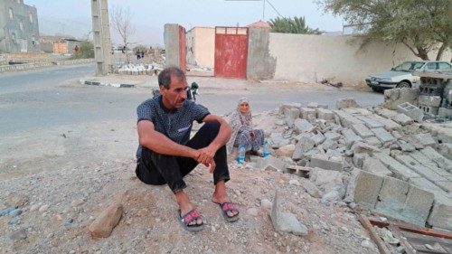 People sit by the rubble amidst destruction in the aftermath of a 6.0 magnitude earthquake in the ...