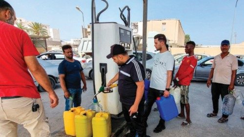 People queue with jerry cans to fill up fuel for home electric generators at a petrol station in ...