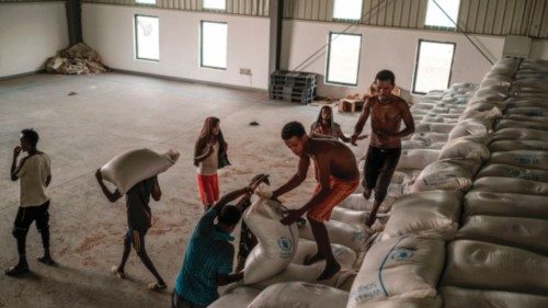 Workers carry sacks of grain in a warehouse of the World Food Programme (WFP) in the city of Abala, ...