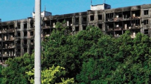 A burned car is pictured in front of a destroyed building in the city of Mariupol on July 1, 2022, ...