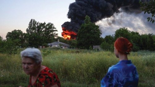 Local residents look on as smoke rises after shelling during Ukraine-Russia conflict in Donetsk, ...