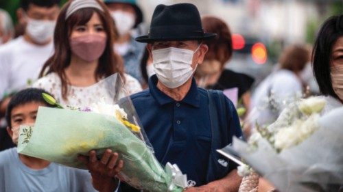 People line up to place flowers at a makeshift memorial outside Yamato-Saidaiji Station, where ...