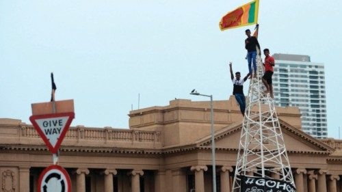 A man waves Sri Lanka's national flag after climbing a tower near presidential secretariat in ...