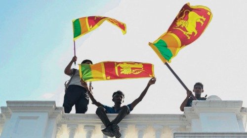 TOPSHOT - Demonstrators wave Sri Lankan flags from a balcony inside the office building of Sri ...