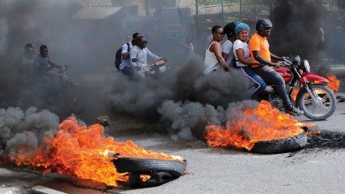 Motorcycle drivers pass through a burning road block as anger mounted over fuel shortages that have ... Motorcycle drivers pass through a burning road block as anger mounted over fuel shortages that have ...