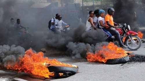 Motorcycle drivers pass through a burning road block as anger mounted over fuel shortages that have ...